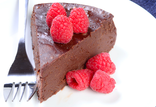 Flourless chocolate cake with raspberries on a white plate