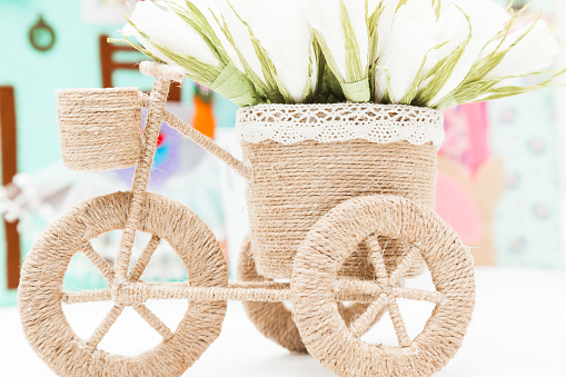 Decorative flower stand in the shape of a small bicycle woven from a natural rope.