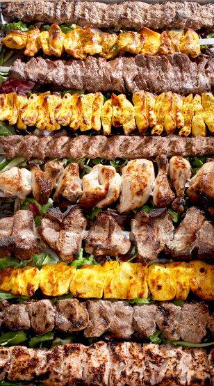 photo of the kebab skewers of various marinated barbecued meats on a bed of greens
