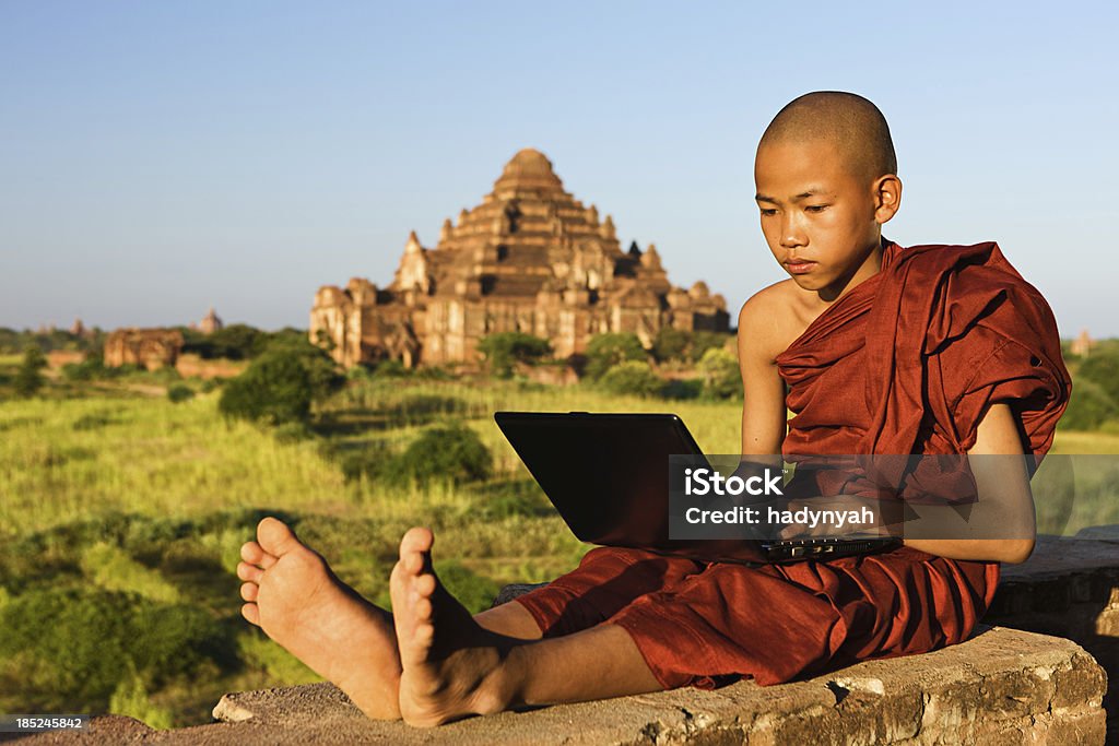 Молодой монах-послушник используя ноутбук - Стоковые фото Bagan Archaeological Zone роялти-фри