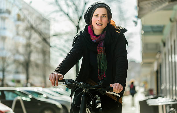 Woman Commuting by Bicycle Woman commuter riding her bicycle on a Berlin city street.  Horizontal shot. moabit stock pictures, royalty-free photos & images