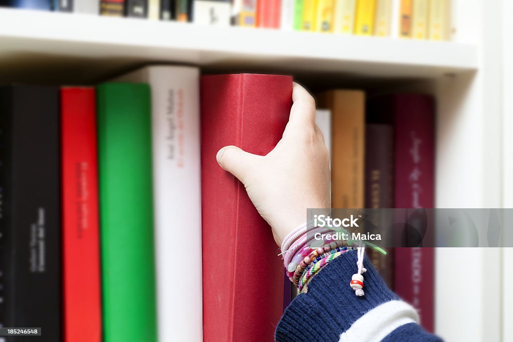 Picking a book Child picks a book. Selective focus on hand and picked book.Children's hand picking a book at a library.Similar: Bookshelf Stock Photo