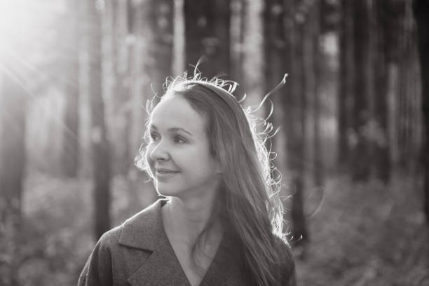 Lady tourist smiles examining forest against blurry trees