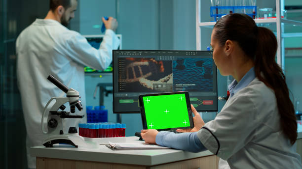 istock Biochemist sitting in laboratory using green mock-up screen tablet 1852467754
