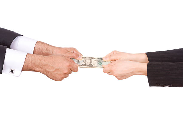 Man and woman's hands pulling on ends of twenty dollar bill stock photo