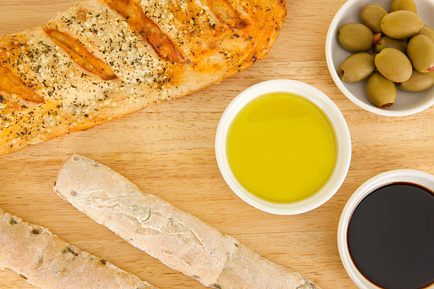 Overhead view of stuffed Olives, balsamic vinegar and olive oil together with olive breadsticks and sundried tomato stromboli on a wooden board. One of a series of bread images.