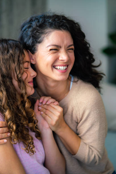 Candid embrace of mother and daughter at home Candid embrace of happy mother and her teenage daughter at home arm span stock pictures, royalty-free photos & images