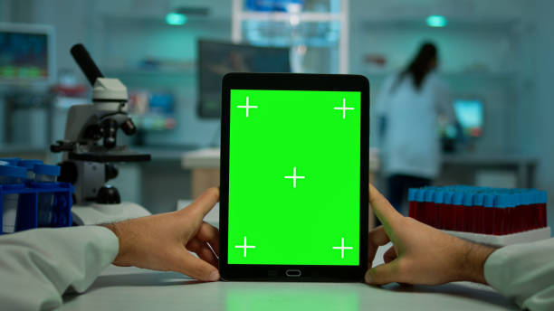 pov-aufnahme eines chemikers, der ein tablet mit greenscreen im labor verwendet - medical texts stock-fotos und bilder