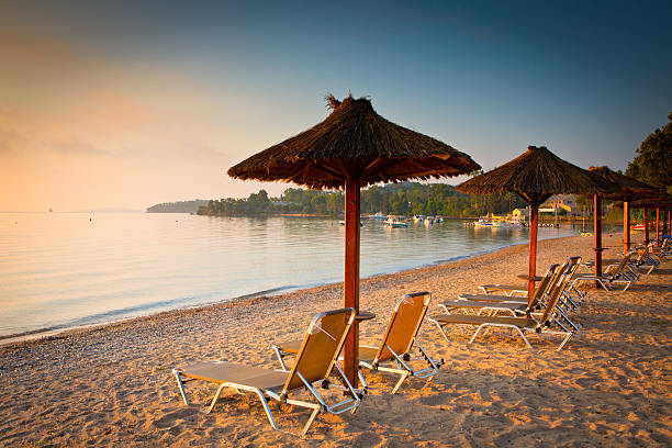 Corfu beach summer beach and row of umbrellas - Corfu - Greece corfu stock pictures, royalty-free photos & images