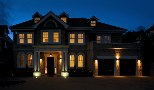 a beautiful and substantial house photographed at dusk with all of the lights switched on. An impressive entrance with black front door is bordered by large double columns and is surrounded with an assortment of windows that are arched on the ground floor.Looking for exterior views of Luxury Homes and Buildings... then please see my other images by clicking on the lightbox Link below...A>A