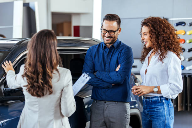 um vendedor de carros está mostrando carros novos para um casal. - professional dealer - fotografias e filmes do acervo