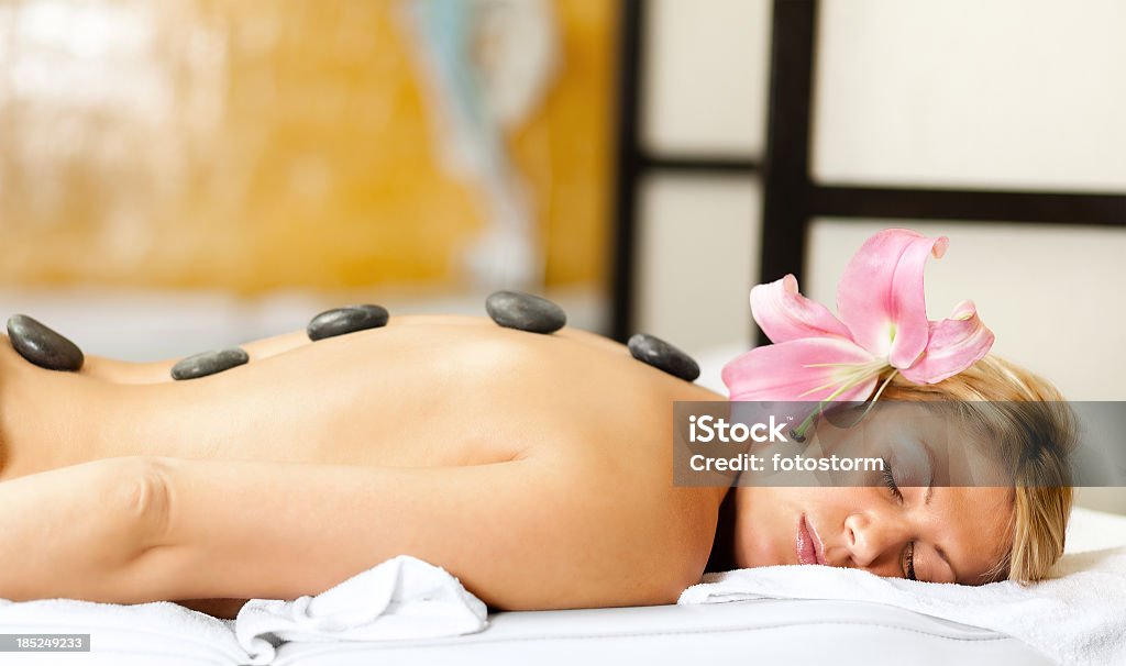 Donna avendo un massaggio con lastones - Foto stock royalty-free di Adulto