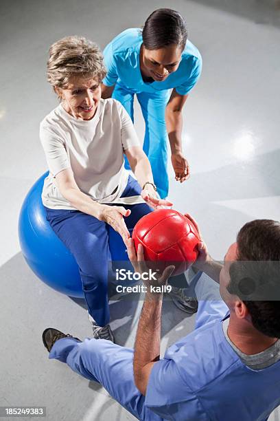 Donna Anziana Con Fisioterapisti Utilizzando Fitness Ball - Fotografie stock e altre immagini di Terapia occupazionale