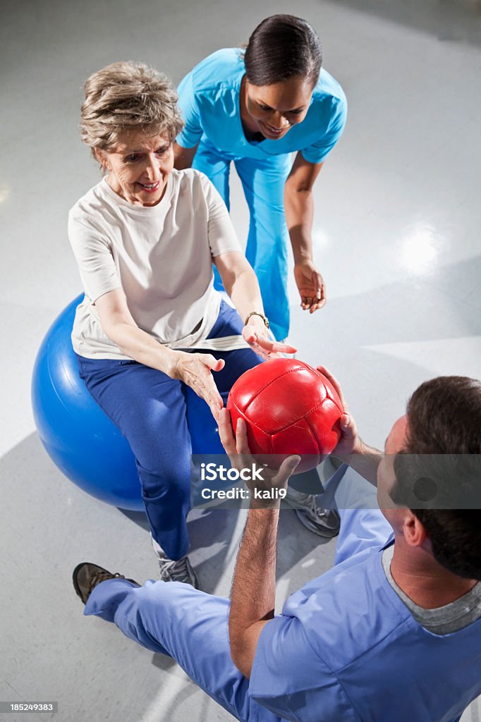 Mulher sênior com físico terapeutas usando bolas de ginástica - Foto de stock de Terapia Ocupacional royalty-free