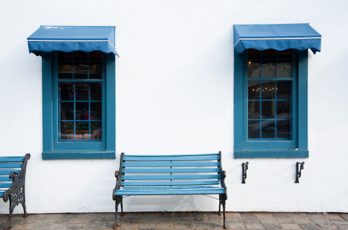 A blue outdoor bench and blue windows with matching blue awnings.