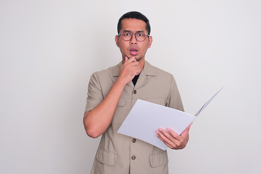 Indonesian government worker showing confuse expression while holding a document