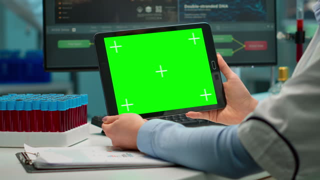 Back view of chemist woman holding tablet with green mockup