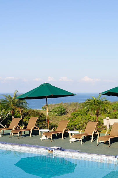 des chaises longues et des parasols au bord de la piscine. - pacific ocean tourist resort day reflection photos et images de collection