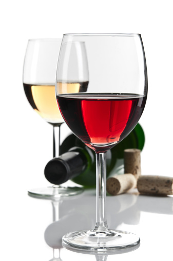 Glass of white and red wine on the background of shelving with bottles of wine