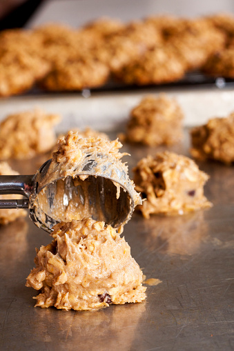 Banana oatmeal chocolate chip cookie dough being scooped onto a baking sheet.