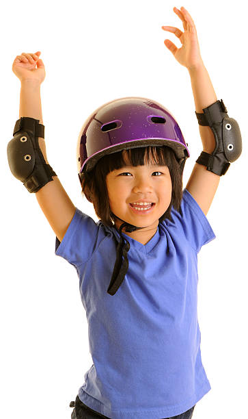 Happy Girl in Biking/Skateboarding Helmet Celebrating "A young girl wearing elbow pads and a biking/skateboarding helmet celebrates, her hands thrown up in the air. White background." elbow pad stock pictures, royalty-free photos & images