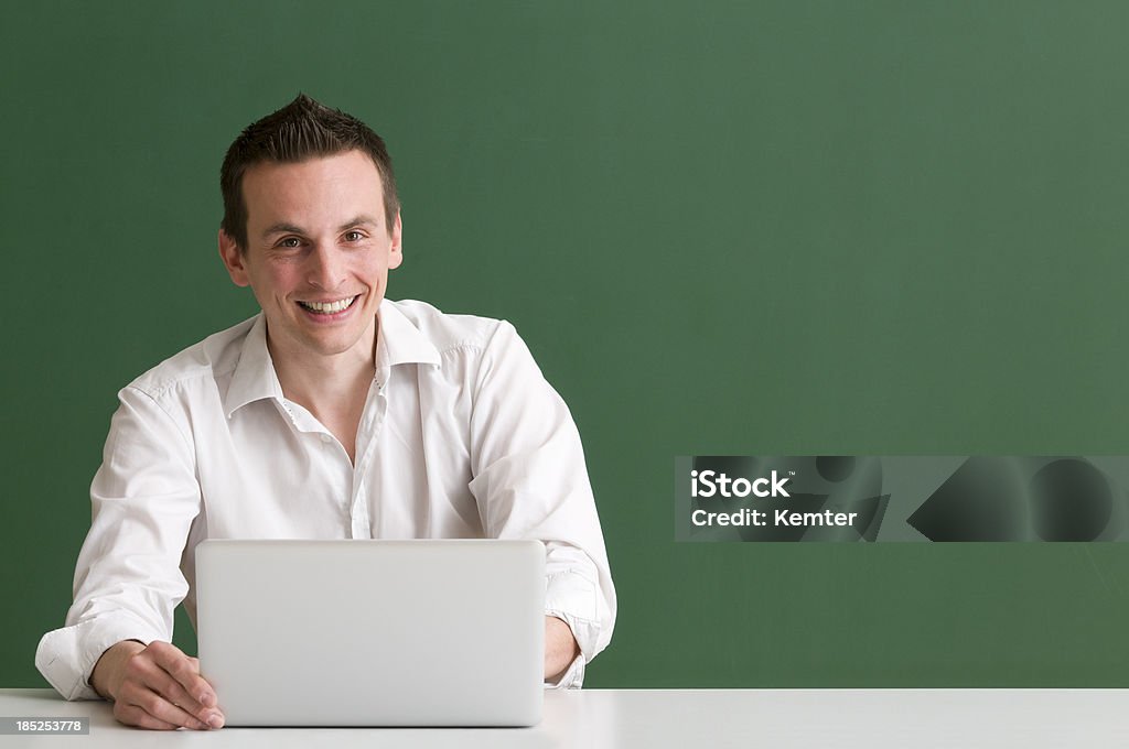 Uomo sorriso mentre si utilizza un computer portatile su sfondo verde - Foto stock royalty-free di Sfondo a colori