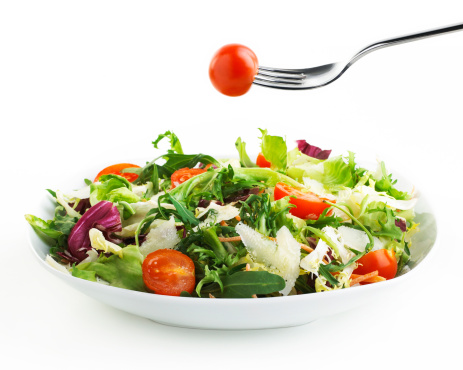 plate of Salad with fork and tomato isolated on white