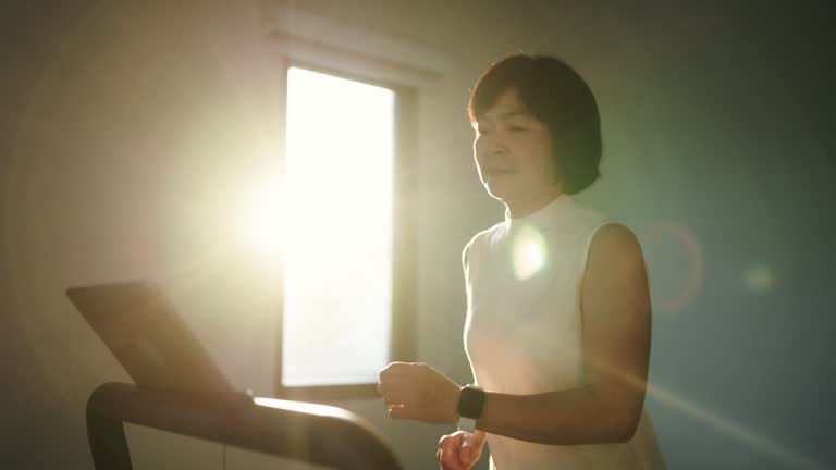 Asian woman jogging on treadmill in the morning.