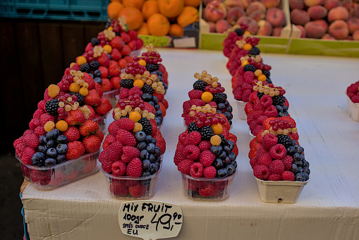 Mix of fresh berries at a street market. Large selection of bright, colorful products. A combination of red, yellow and dark blue colors. The famous Havel market in the historical center of Prague.