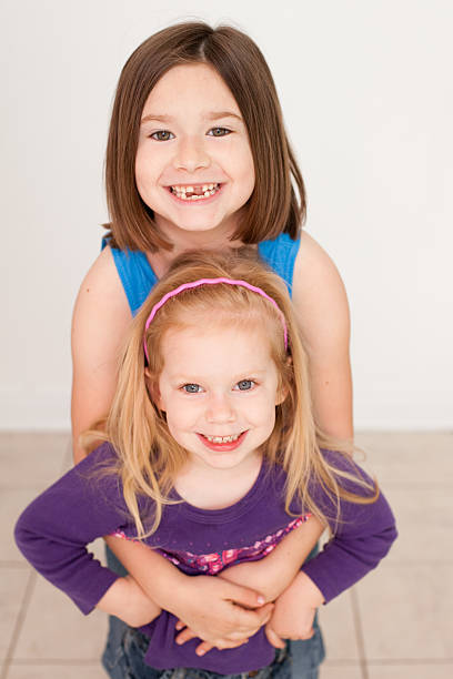 imagem a cores de grande irmã menina dando um abraço - embracing smiling gap children only - fotografias e filmes do acervo