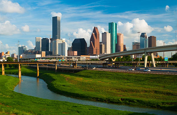 Houston skyline, freeway, and river Houston downtown skyline with beautiful clouds in the background and Interstate 10 freeway and Whiteoak bayou in the foreground. houston skyline stock pictures, royalty-free photos & images