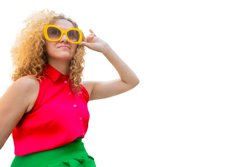 Young blonde woman with long curly hair in red and green closes in sun glasses playful smile happy positive