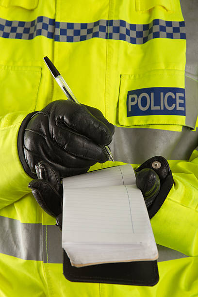 Police officer jotting down details in his notepad A UK policeman taking notes, possibly at a crime scene. metropolitan police stock pictures, royalty-free photos & images