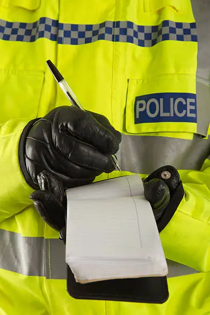 Photo of Police officer jotting down details in his notepad