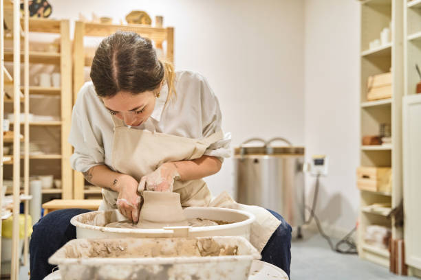 художник лепит глиняный горшок на прялке, глубоко сосредоточенный - kiln ceramic ceramics fire стоковые фото и изображения