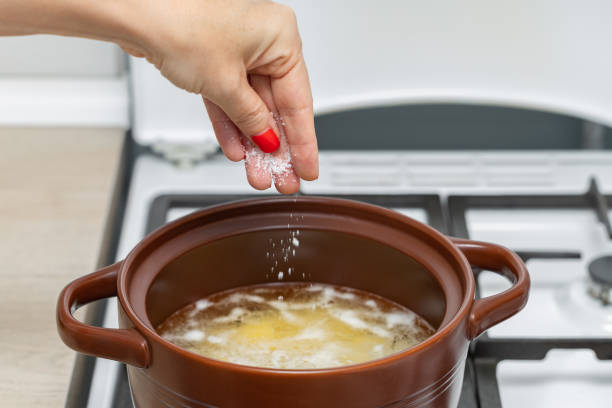 istock woman's hand salts water in a pan 1852553321