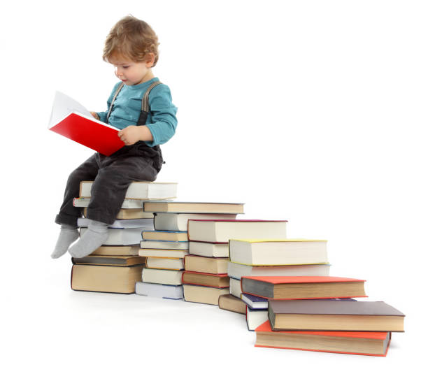 Toddler boy reading on a book staircase stock photo