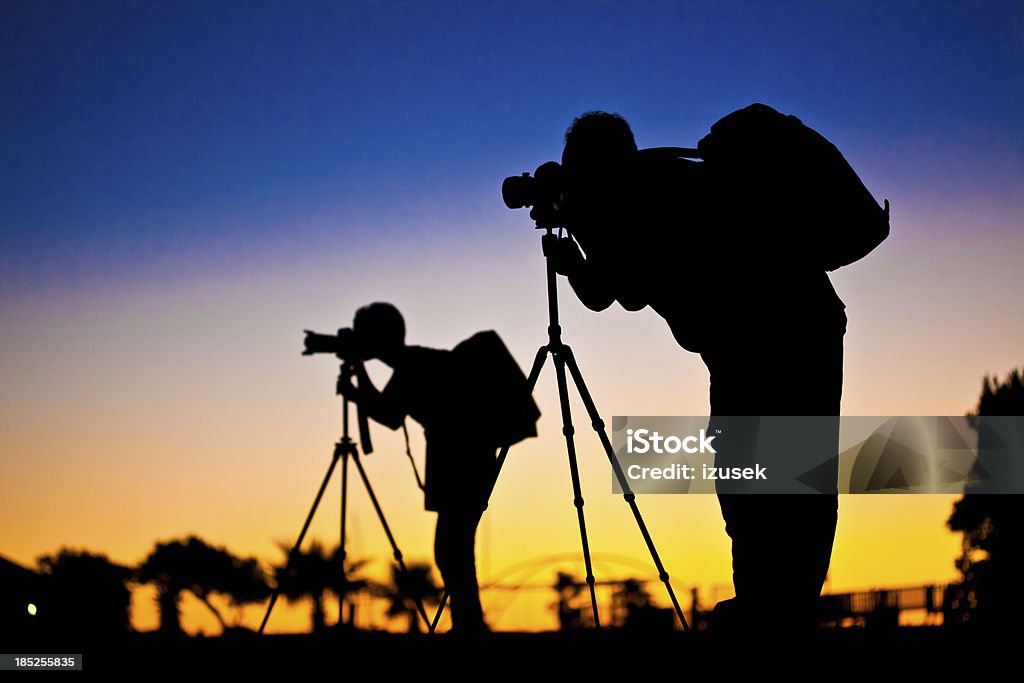 Silhouette of photographers Silhouette of two photographer at sunset Adult Stock Photo