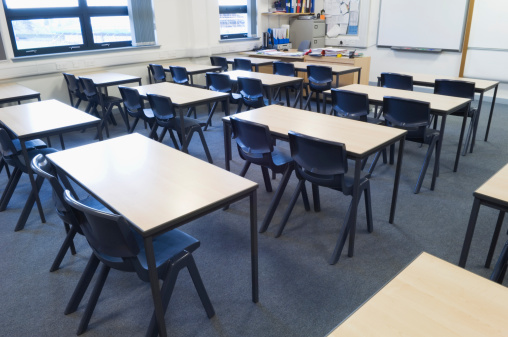 Empty classroom with desks and chairs in a line