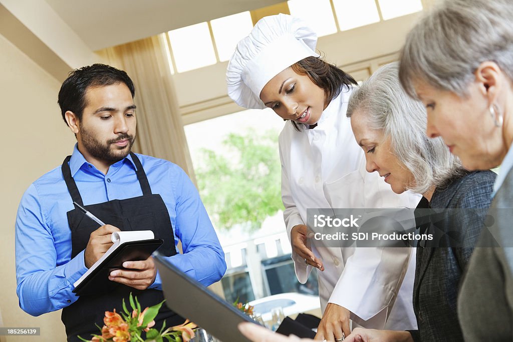 Chef y restaurante camarero ayudar a los clientes en la orden - Foto de stock de Cliente libre de derechos