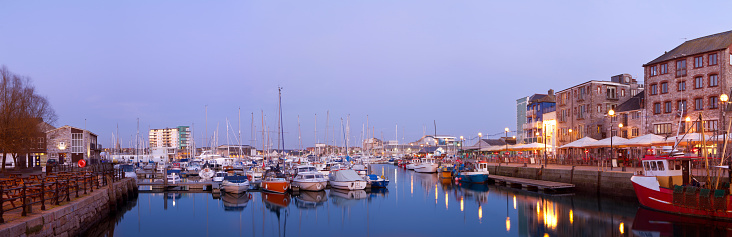 A panoramic scene of Plymouth Barbican at twilight. A popular location for tourist and residence to Plymouth. The scene shows a calm harbour with restaurants and bars to the left of the frame. A historic art of Plymouth.
