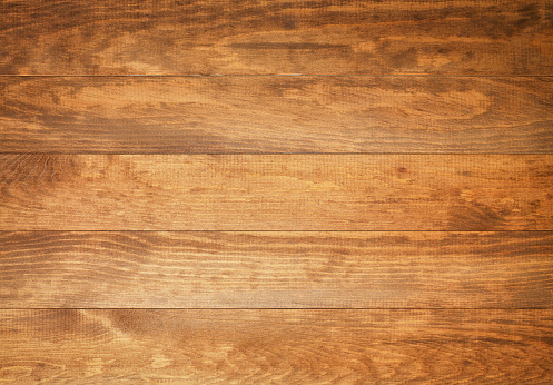 A photograph of five planks of wood laid side by side and running horizontally across the frame.  The wood is light brown with darker brown lines and swirls visible.  The top plank has arches along its length, the points towards the left, the trailing ends towards the right.  The second plank has a large light brown oval in the center top, with thin-lined ovals surrounding it.  The center plank has a slight discoloration to the lower right.  The fourth plank has thick brown lines going from end to end, with lighter brown lines between.  The bottom plank has swirls along the bottom.