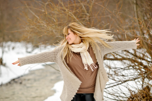 happy woman in winter time with arms raised and flying hair.