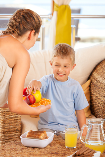 Young mother serving fresh fruits to her son.