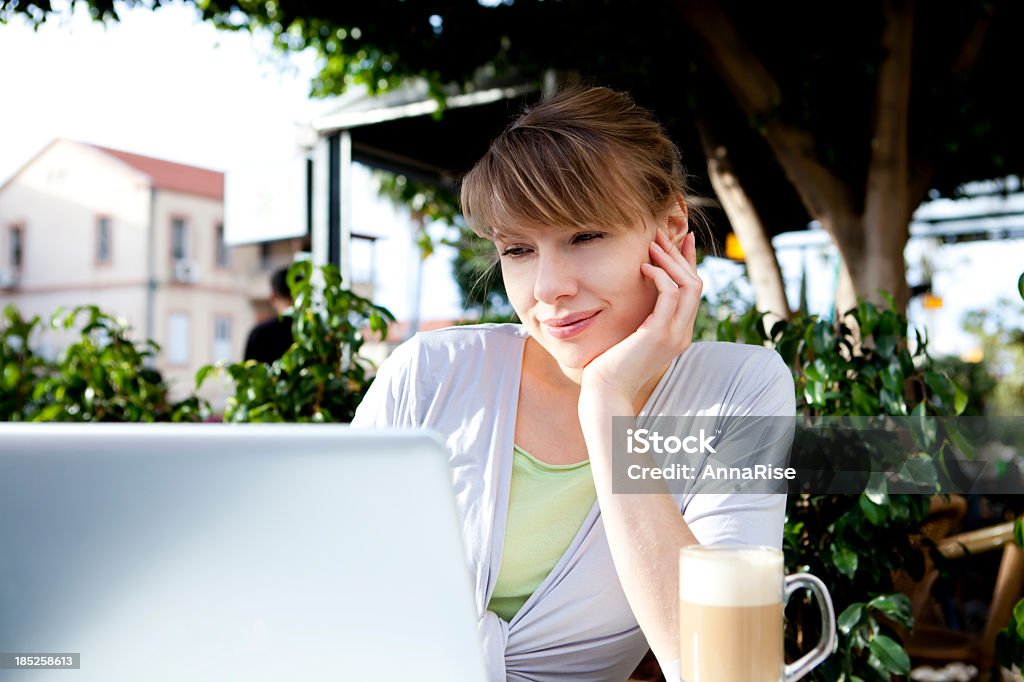 Donna utilizzando un computer portatile In Café - Foto stock royalty-free di 20-24 anni