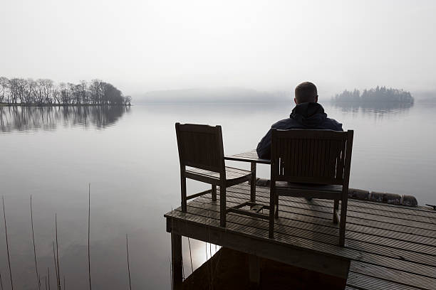 Lonely male sitting beside a Loch.