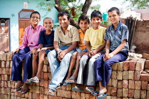 Cheerful Group of Rural Indian Children sitting on a pile of Bricks