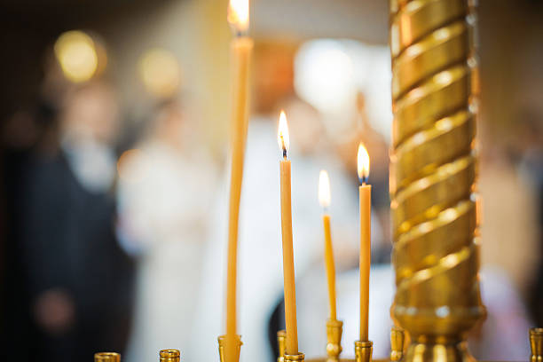 Burning candles in a Russian ortodox church. Close-up of ordinary church interior. Selective focus. With wedding ceremony on background.