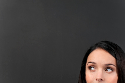 Woman thinking in front of empty blackboard background