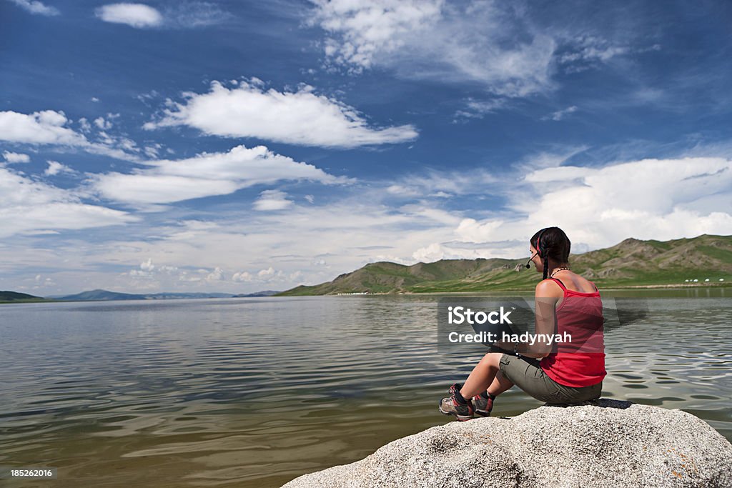 Mujer joven con ordenador portátil en el rock - Foto de stock de Lago libre de derechos